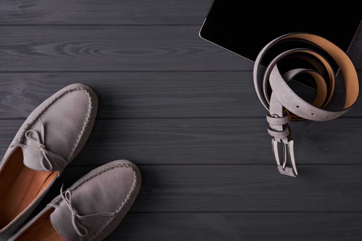 Elegant suede man's moccasins shoes with a belt over grey planks
